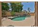 Backyard view of kidney-shaped pool with trees, rock waterfall feature, and patio at 16126 N 159Th Dr, Surprise, AZ 85374