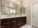 Elegant bathroom featuring double sinks with dark wood cabinets and a large mirror at 1643 N 144Th Dr, Goodyear, AZ 85395