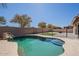 Backyard pool with rock feature, steps, and mature trees in a desert landscaped yard at 16836 W Vereda Solana Dr, Surprise, AZ 85387