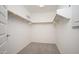 Bright walk-in closet with neutral carpet, wood rods and built in shelving at 18344 W Getty Dr, Goodyear, AZ 85338