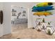 Stylish living room with a grey couch, tile floors, shelving decor, and surfboard at 22670 N Kennedy Dr, Maricopa, AZ 85138