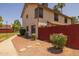 Two-story tan home with a red fence and desert landscaping featuring shrubs and stepping stones at 2455 E Broadway Rd # 122, Mesa, AZ 85204
