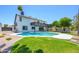 Spacious backyard featuring a sparkling pool, lush green lawn, and a charming two-story home with a balcony at 2552 S Playa --, Mesa, AZ 85202