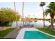 Beautiful backyard view with a pool and dock on the water surrounded by lush palm trees and well-maintained landscaping at 2552 S Playa --, Mesa, AZ 85202