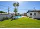 Well-manicured backyard with a sparkling pool, lush green lawn, and mature palm trees at 2608 W Aster Dr, Phoenix, AZ 85029