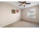 This is a well-lit bedroom with neutral carpet and a window that brings in natural light at 3021 E Harmony Cir, Mesa, AZ 85204