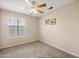 This is a cozy bedroom with neutral carpet, a ceiling fan, and a window to let natural light in at 3021 E Harmony Cir, Mesa, AZ 85204