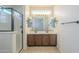 Bathroom featuring double sinks, tile floors, framed mirrors, and a glass-enclosed shower at 3451 S Wren Dr, Gilbert, AZ 85297