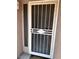 A beige house exterior showing a storm door with security bars next to a window at 3510 E Hampton Ave # 133, Mesa, AZ 85204
