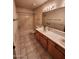 Bathroom featuring a vanity with dual sinks, decorative wallpaper, and a shower-tub combination at 3853 W Calle Lejos --, Glendale, AZ 85310