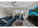 Bright living room featuring a large blue sectional, ceiling fan, shuttered windows and neutral walls at 3915 N Shannon Cir, Mesa, AZ 85215