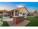 Beautiful backyard with a built-in grill, putting green, and outdoor dining area at dusk at 4029 N 160Th Dr, Goodyear, AZ 85395