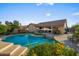 Beautiful backyard pool with a built-in seating area, mature landscaping, and an outdoor patio at 4029 N 160Th Dr, Goodyear, AZ 85395