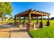 Community pavilion with stone columns, wooden beams, and picnic tables set on a grassy lawn at 4251 E Sundance Ave, Gilbert, AZ 85297