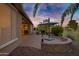 Paver patio with dining and grill, desert landscaping, and vibrant sunset reflecting in windows at 42711 W Darter Dr, Maricopa, AZ 85138