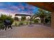 Paver patio with a grill, desert landscaping, and an umbrella against a vibrant sunset sky at 42711 W Darter Dr, Maricopa, AZ 85138