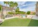 Spacious backyard featuring artificial grass, a pergola-covered dining area, and a luxurious pool at 5542 W Big Oak St, Phoenix, AZ 85083