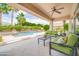 Covered patio area with comfortable seating, ceiling fan, and views of the sparkling pool and lush landscaping at 5542 W Big Oak St, Phoenix, AZ 85083