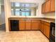 A kitchen view showcasing wooden cabinets, black appliances, and an open layout to an adjacent room at 6388 W Ruth Ave, Glendale, AZ 85302