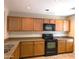 A kitchen with matching wooden cabinets, black appliances, neutral countertops, and recessed lighting at 6388 W Ruth Ave, Glendale, AZ 85302