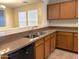 A kitchen featuring wood cabinets, tile floors, stainless steel sink, and black dishwasher at 6388 W Ruth Ave, Glendale, AZ 85302