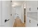 Hallway featuring wood floor, white walls, and modern black hardware on the doors and cabinets at 6908 E Windsor Ave, Scottsdale, AZ 85257