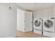 Bright laundry room featuring modern washer and dryer set, wood-look floor, and a white door at 6908 E Windsor Ave, Scottsdale, AZ 85257