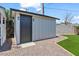 Side view of backyard shed with black door, landscaping stones, artificial grass at 6908 E Windsor Ave, Scottsdale, AZ 85257