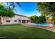 Backyard with green grass, a pool, covered patio, and well-maintained landscaping surrounding the home at 7247 W Buckskin Trl, Peoria, AZ 85383