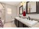 Bright bathroom featuring double sinks with granite countertops, decorative framed mirrors, and tiled floor at 7247 W Buckskin Trl, Peoria, AZ 85383