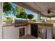 Outdoor kitchen features a grill, counter space, a small refrigerator, and storage with a sink at 7247 W Buckskin Trl, Peoria, AZ 85383
