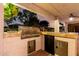 An outdoor kitchen features a built-in grill, counter space, a small refrigerator, and storage at twilight at 7247 W Buckskin Trl, Peoria, AZ 85383
