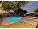 Backyard pool with a sun shelf surrounded by mature trees and desert landscaping at 7247 W Buckskin Trl, Peoria, AZ 85383