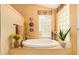 Bathroom showcasing a large soaking tub, tiled walls, glass block window, and decorative accents at 7722 W Michigan Ave, Glendale, AZ 85308