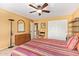 Bright bedroom featuring a ceiling fan, dresser, and a comfortable bed with striped bedding at 7722 W Michigan Ave, Glendale, AZ 85308