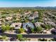 High angle, showcases desert neighborhood, large modern homes, lush landscaping, and breathtaking mountain views in the background at 7775 E Fledgling Dr, Scottsdale, AZ 85255