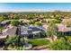 Aerial view of a backyard featuring a pristine lawn and patio complemented by mature trees and mountain views at 7775 E Fledgling Dr, Scottsdale, AZ 85255