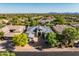 Aerial shot of home with lush landscaping, gray tile roof, complemented by mature trees and mountain views in the background at 7775 E Fledgling Dr, Scottsdale, AZ 85255