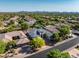 Wide aerial view of desert neighborhood, and large home with gray roof, desert landscaping, and mountain views at 7775 E Fledgling Dr, Scottsdale, AZ 85255