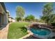 Landscaped backyard features manicured lawn, mature trees, and a charming stone spa with waterfall feature at 7775 E Fledgling Dr, Scottsdale, AZ 85255