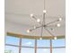 Modern chandelier with exposed bulbs set against a backdrop of curved windows and blue skies at 7775 E Fledgling Dr, Scottsdale, AZ 85255