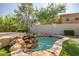 Backyard hot tub with a rock feature, providing a relaxing spa-like experience in a lush outdoor setting at 7775 E Fledgling Dr, Scottsdale, AZ 85255