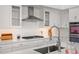 Modern kitchen featuring white cabinetry, stainless steel range hood, gas cooktop, and a sleek faucet at 7775 E Fledgling Dr, Scottsdale, AZ 85255