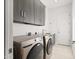 Well-lit laundry room features washer, dryer, storage cabinets, and sleek countertop at 7775 E Fledgling Dr, Scottsdale, AZ 85255