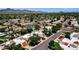 Expansive aerial view of a neighborhood featuring lush trees, mountain views, and a community swimming pool at 9322 E Jenan Dr, Scottsdale, AZ 85260