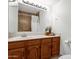 Cozy bathroom featuring traditional wood cabinetry, a large mirror, and shower with earth-tone tile at 9322 E Jenan Dr, Scottsdale, AZ 85260