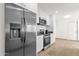 Close-up of the kitchen's stainless steel refrigerator, stove, and microwave, complemented by white cabinets and tile backsplash at 9322 E Jenan Dr, Scottsdale, AZ 85260