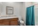 Neutral toned bathroom with wood cabinets, granite countertop and teal shower curtain at 1166 W Silver Creek Ln, Queen Creek, AZ 85140