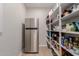 Well-stocked pantry with stainless steel refrigerator and wood shelving at 1166 W Silver Creek Ln, Queen Creek, AZ 85140