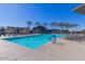 A resort-style pool with palm trees, lounge chairs, and a covered area for relaxing at 1166 W Silver Creek Ln, Queen Creek, AZ 85140